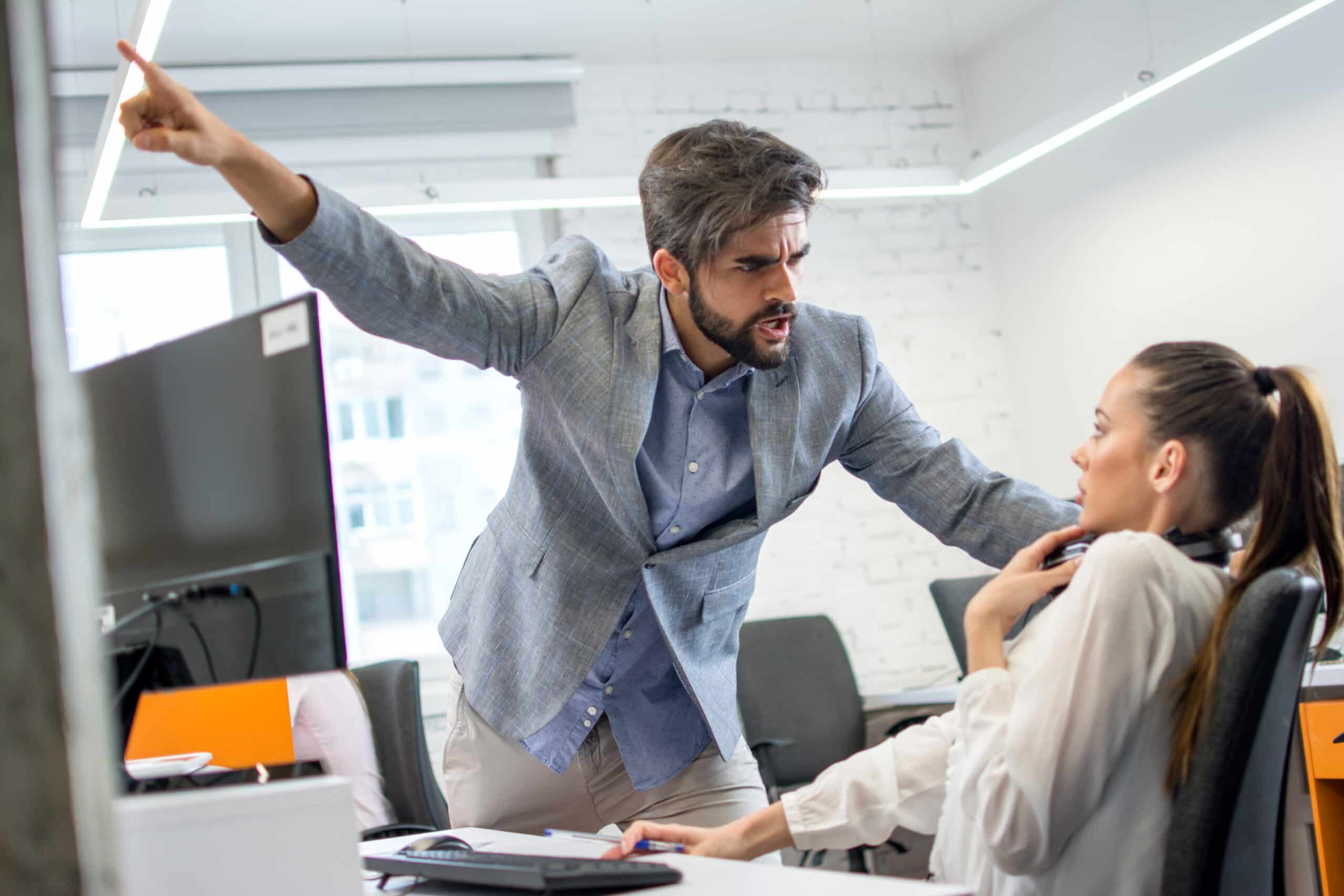 Angry boss firing upset female employee in office. Young male business manager yelling at scared and stressed business woman at her workplace who needs a retaliation attorney san diego.